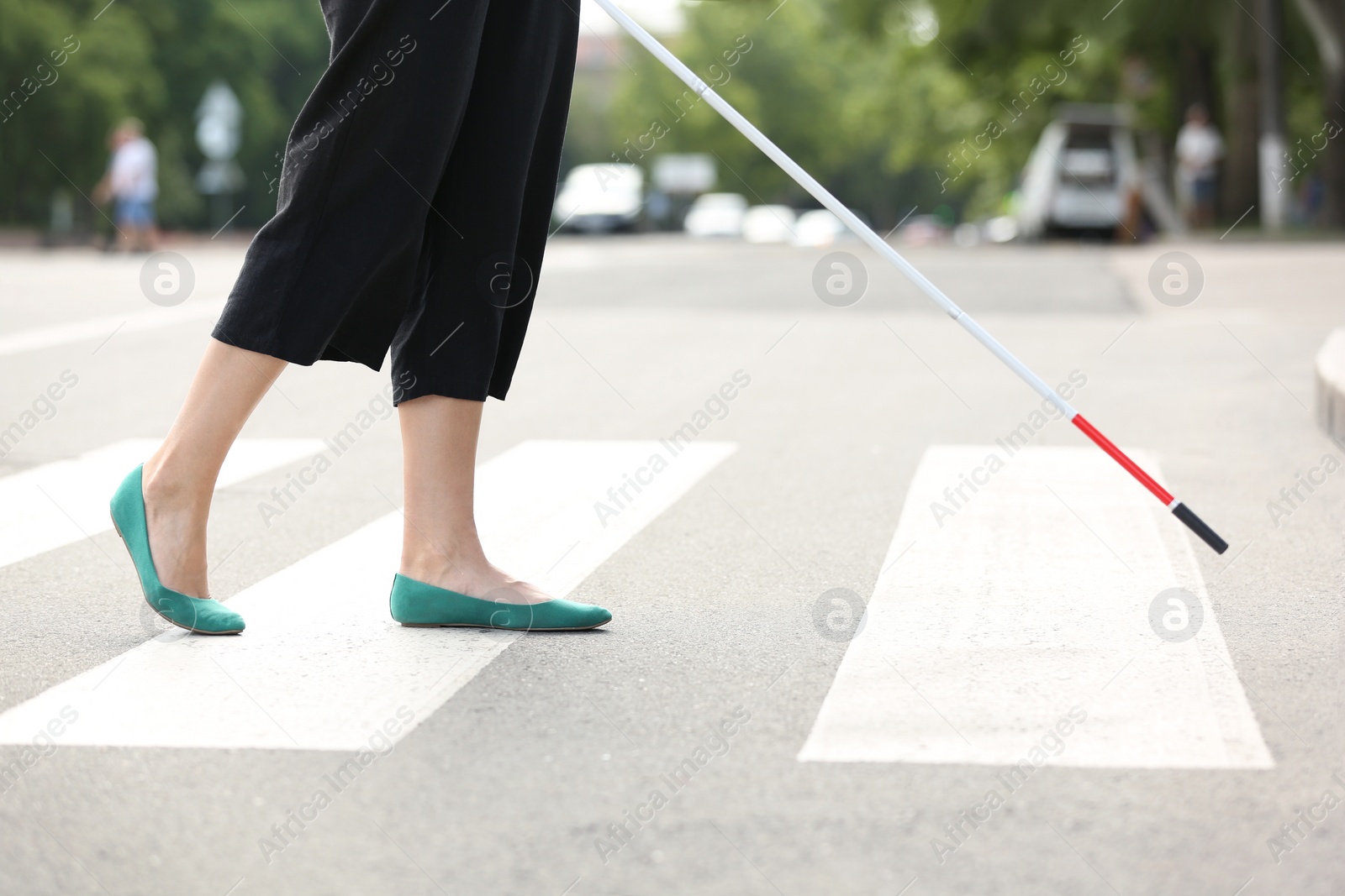 Photo of Blind person with long cane crossing road, closeup