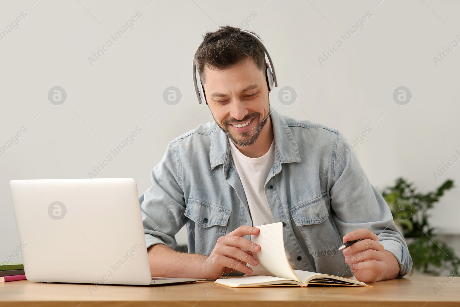 Photo of Man in headphones studying on laptop at home. Online translation course