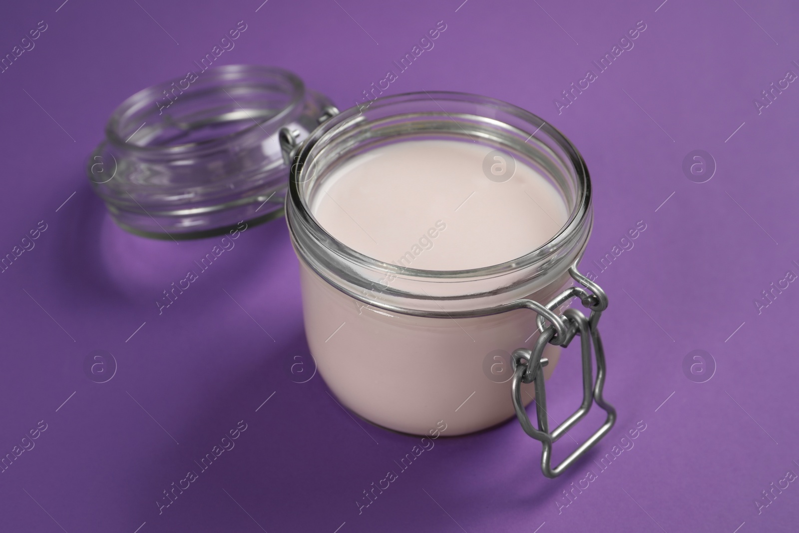 Photo of Jar of tasty organic yogurt on purple background