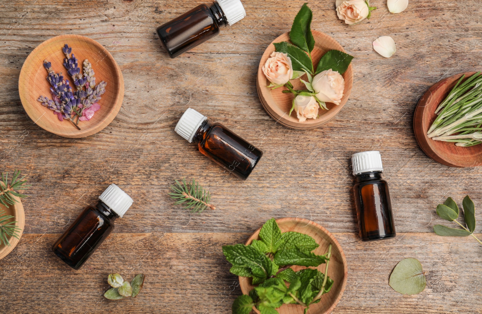 Photo of Different essential oils and ingredients on wooden background, flat lay