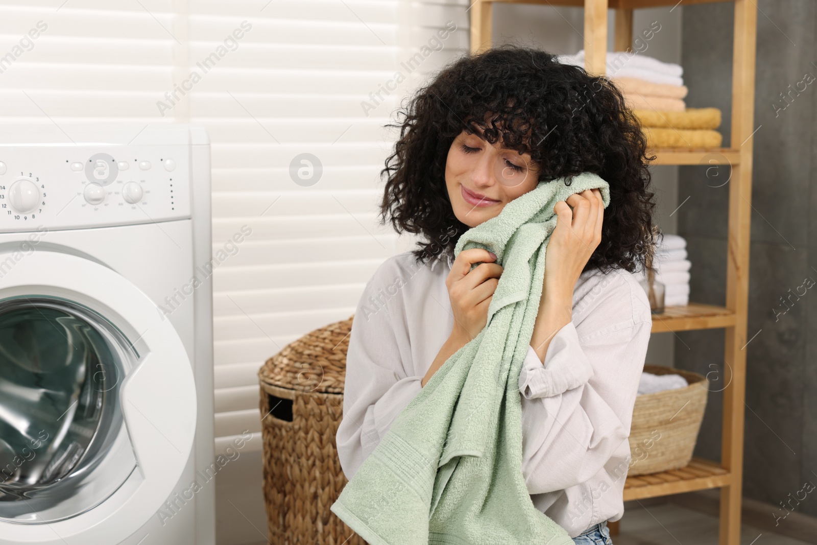 Photo of Woman with laundry near washing machine indoors