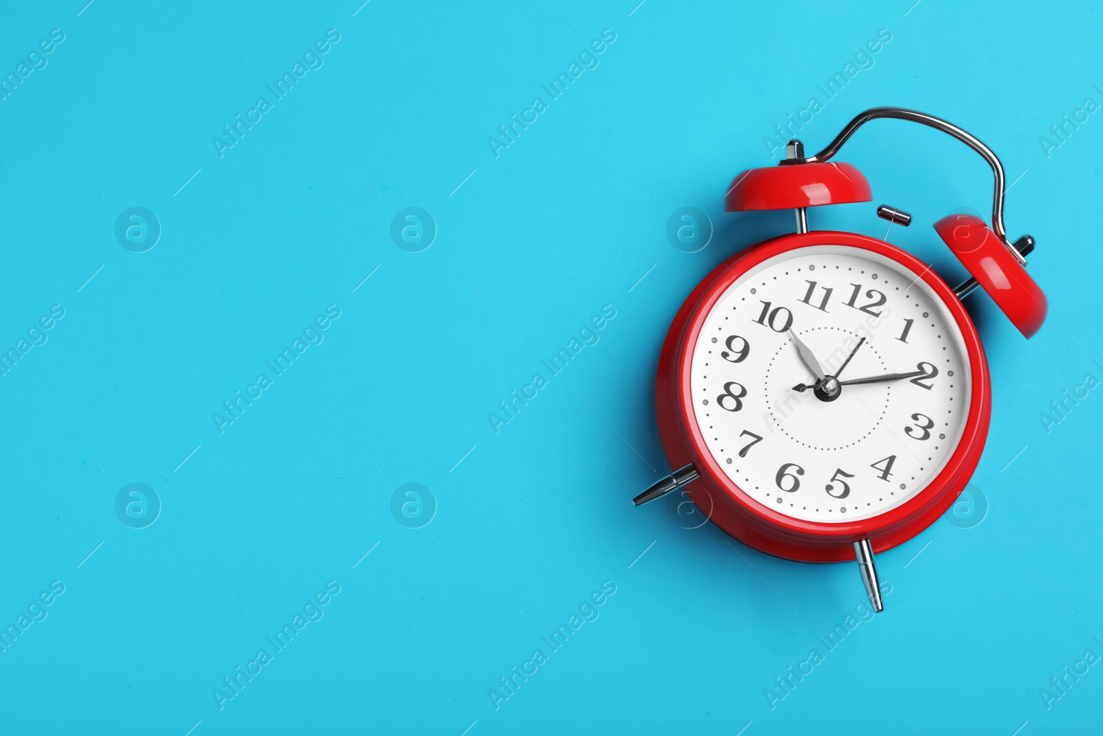 Photo of Alarm clock on light blue background, top view with space for text. School time