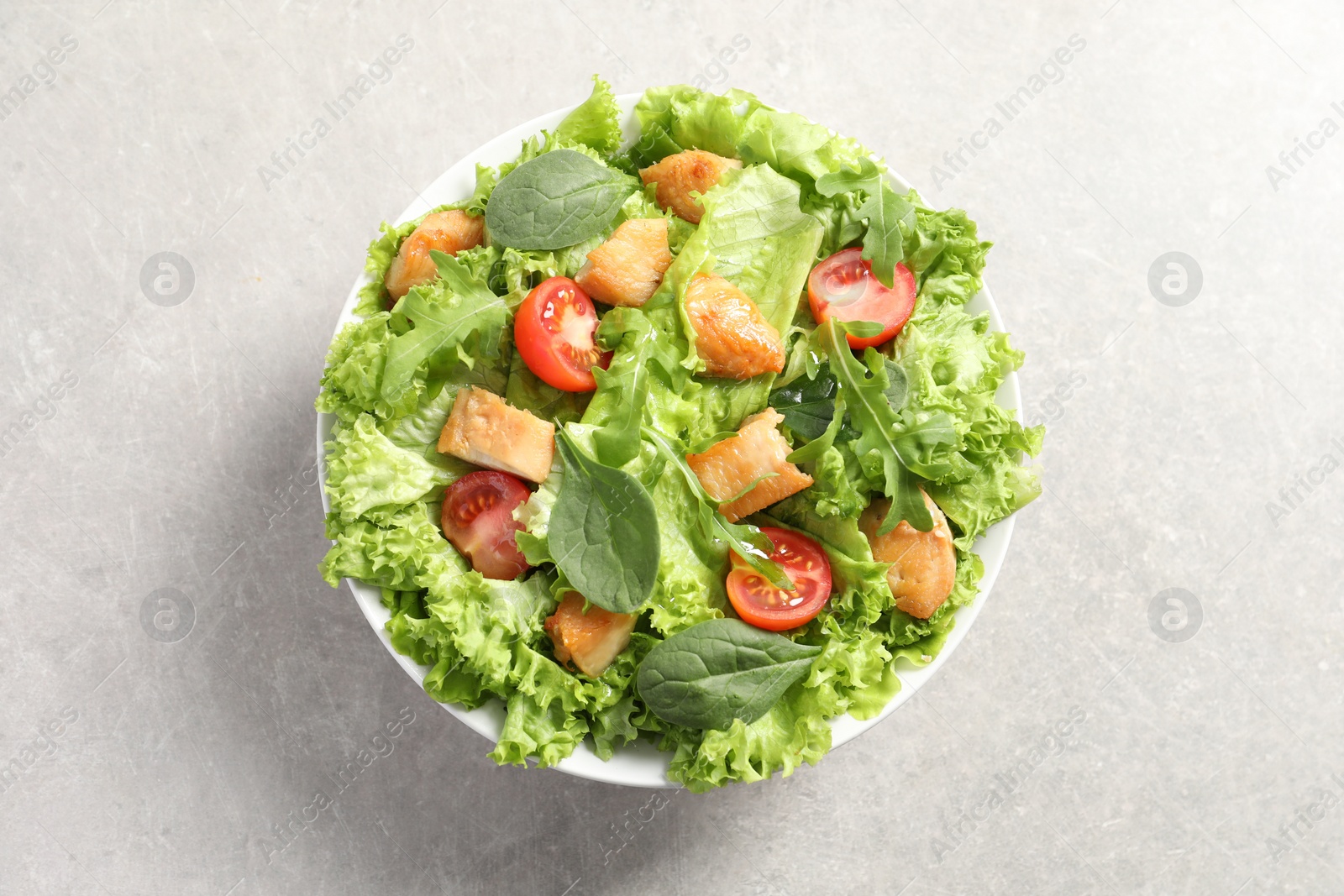 Photo of Delicious salad with chicken, cherry tomato and spinach on light grey table, top view