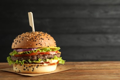 Photo of Burger with delicious patty on wooden table, space for text