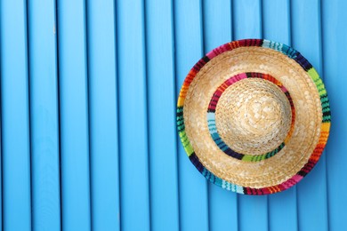 Photo of Mexican sombrero hat on blue wooden surface, top view. Space for text