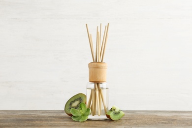 Photo of Aromatic reed freshener and kiwi on wooden table against light background