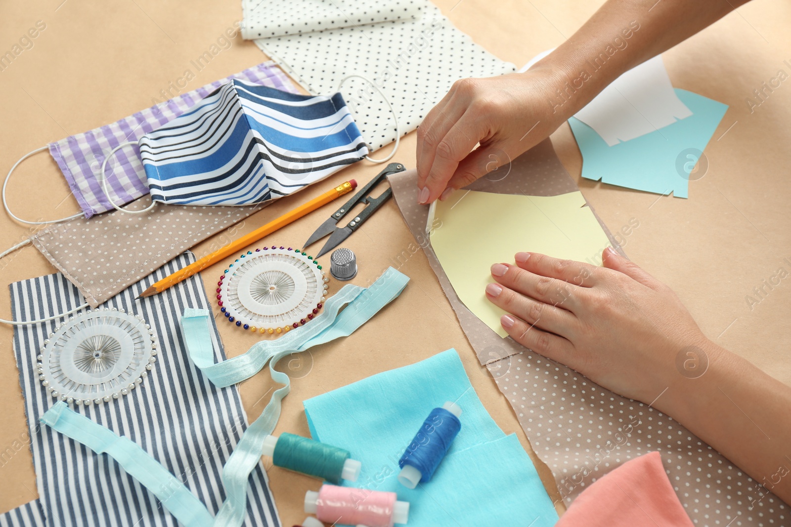 Photo of Woman making sewing template for cloth mask at table, closeup. Personal protective equipment during COVID-19 pandemic