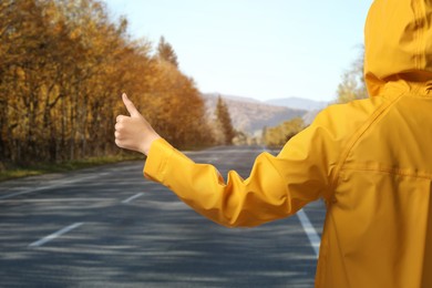 Image of Woman catching car on road, closeup. Hitchhiking trip