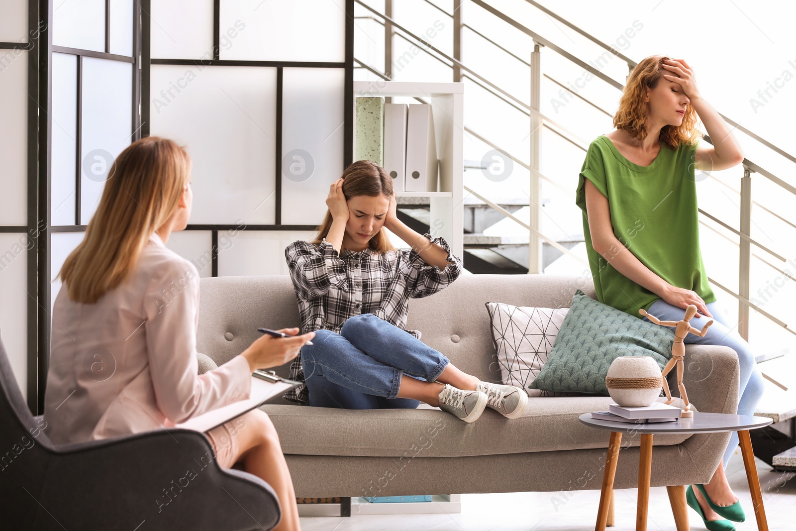 Photo of Young woman and her teenage daughter visiting child psychologist in office