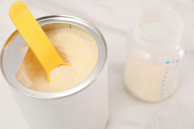 Can of powdered infant formula with scoop on table, closeup. Baby milk