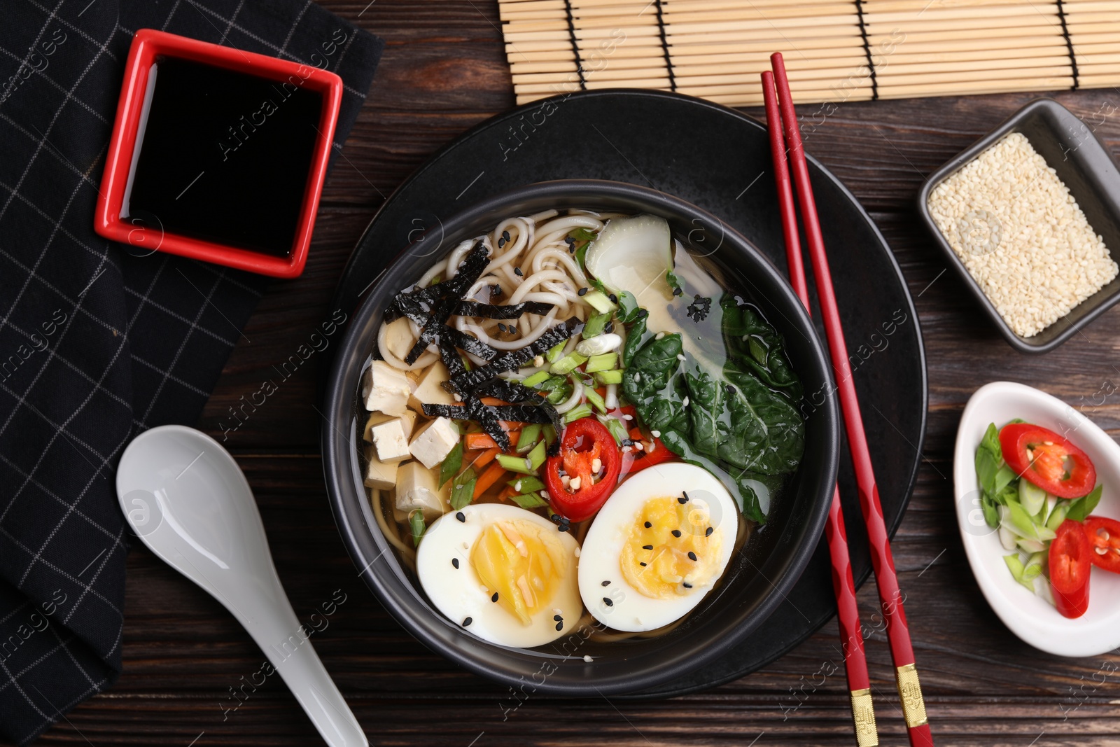 Photo of Delicious vegetarian ramen served on wooden table, flat lay. Noodle soup