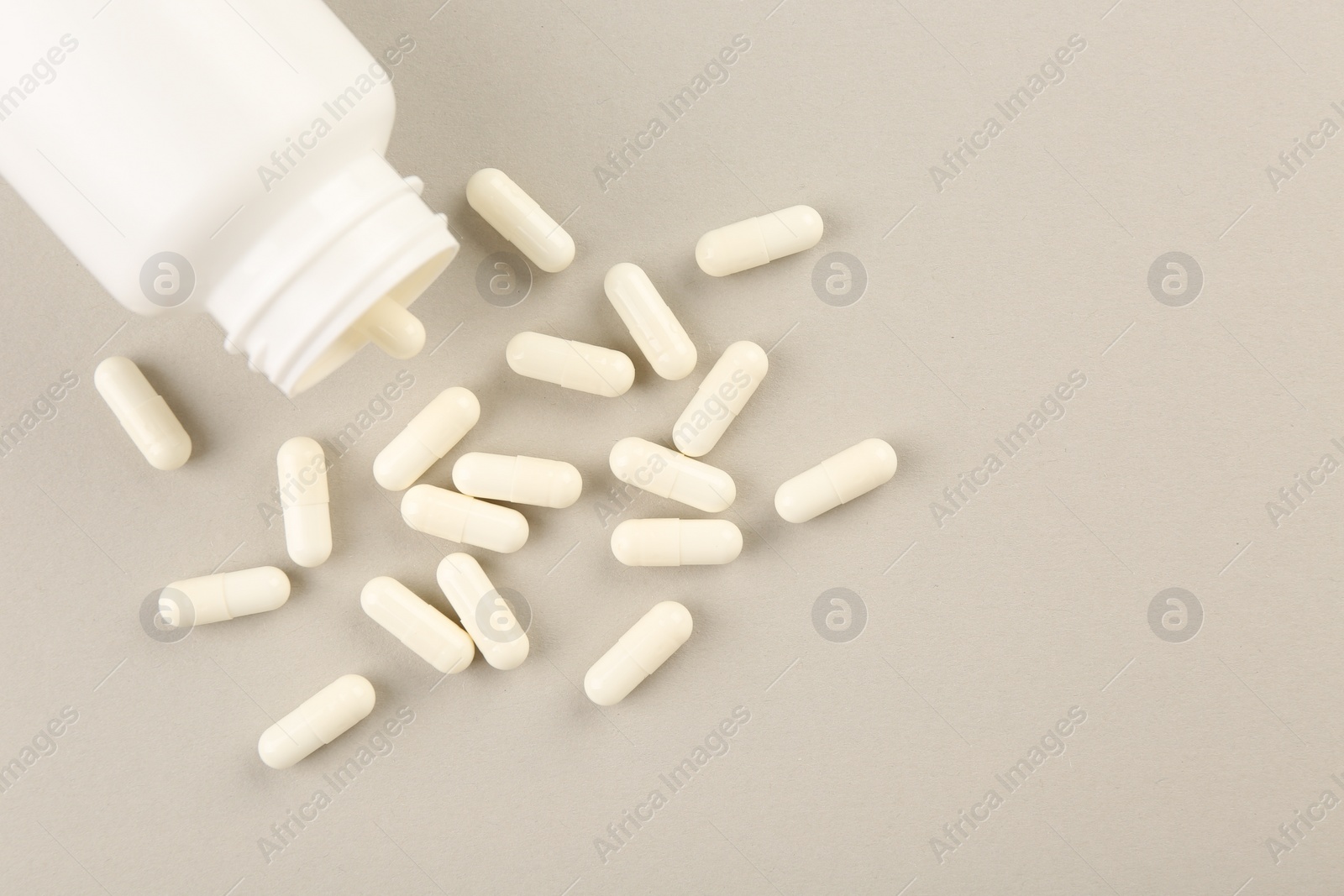 Photo of Bottle and vitamin capsules on light background, top view. Space for text