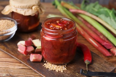 Tasty rhubarb sauce and ingredients on wooden table, closeup