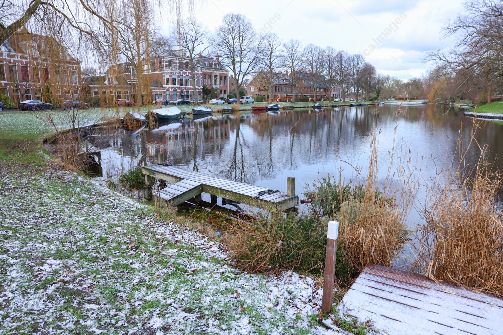 Photo of Picturesque view of water canal with moored boats in city on winter day