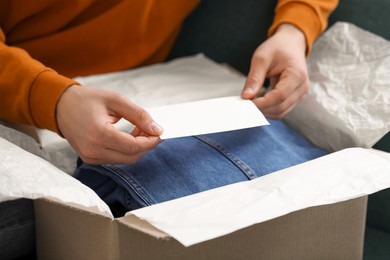 Man holding greeting card near parcel with Christmas gift, closeup