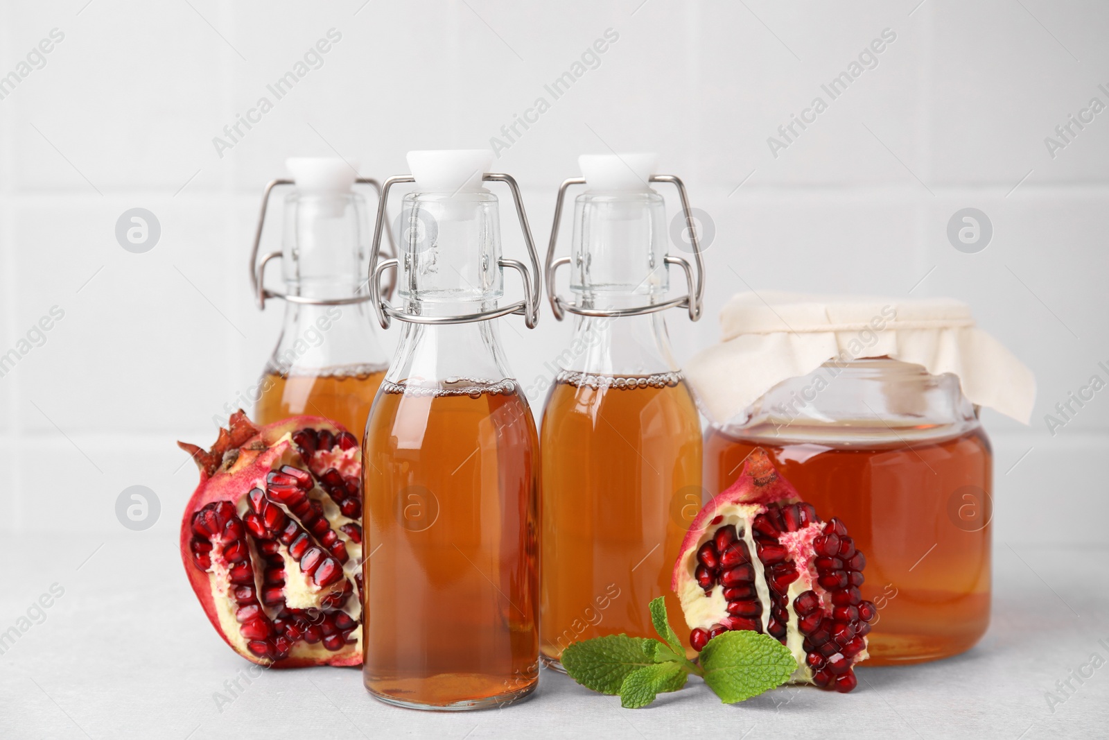 Photo of Tasty kombucha, pomegranate and mint on white table