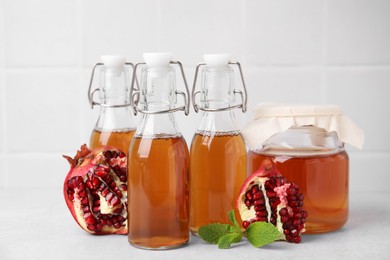 Photo of Tasty kombucha, pomegranate and mint on white table