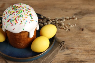 Photo of Tasty Easter cake, decorated eggs and willow branches on wooden table. Space for text