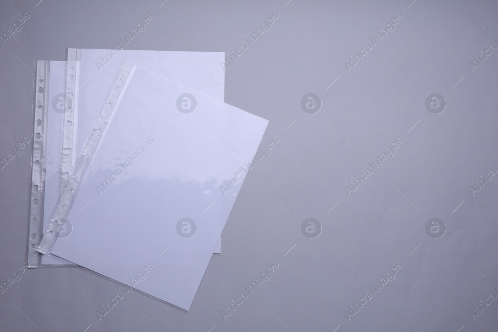 Photo of Punched pockets with paper sheets on light grey background, flat lay. Space for text