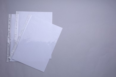 Photo of Punched pockets with paper sheets on light grey background, flat lay. Space for text