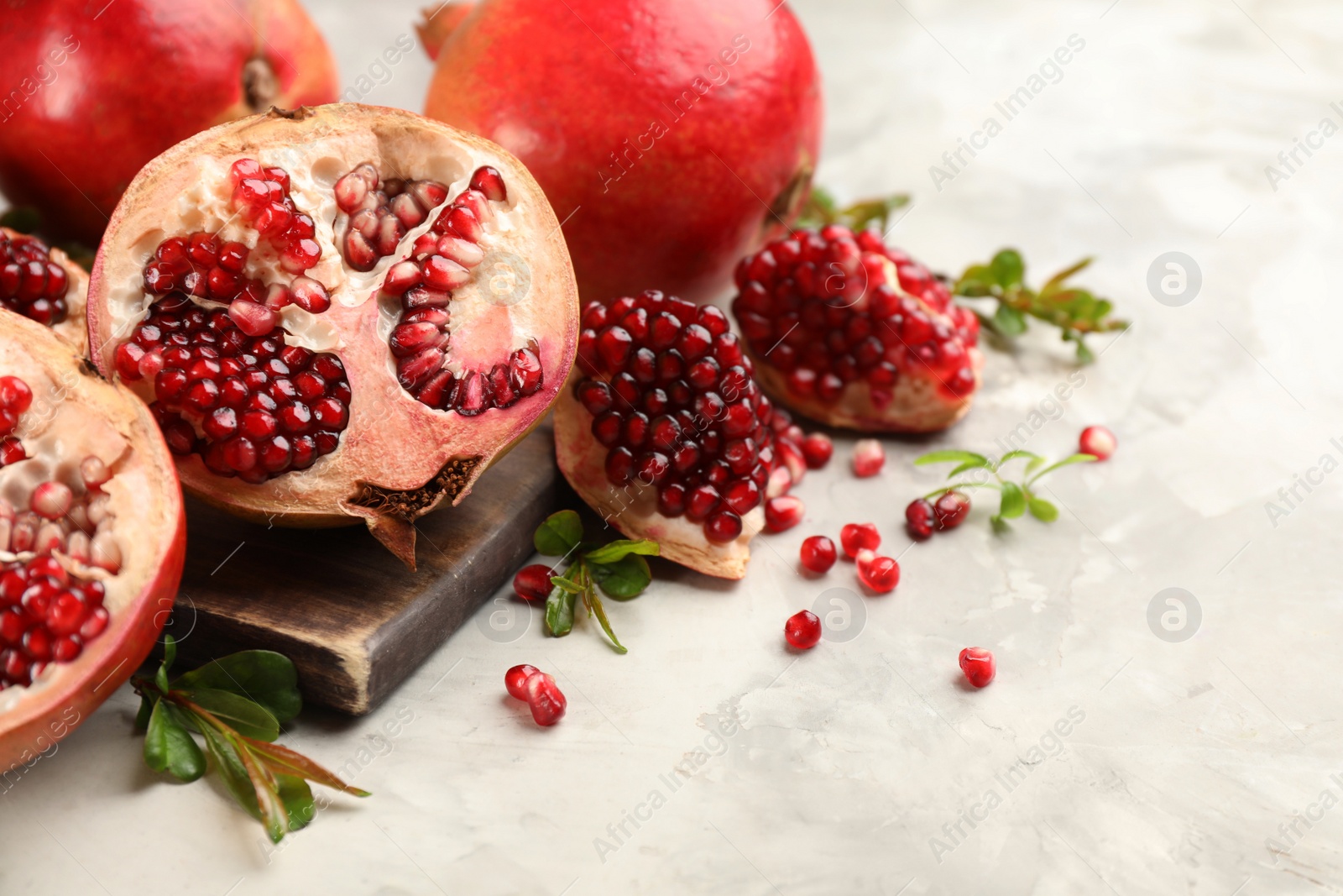 Photo of Delicious ripe pomegranates on grey table, closeup. Space for text