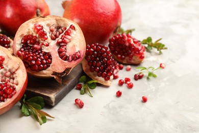 Delicious ripe pomegranates on grey table, closeup. Space for text