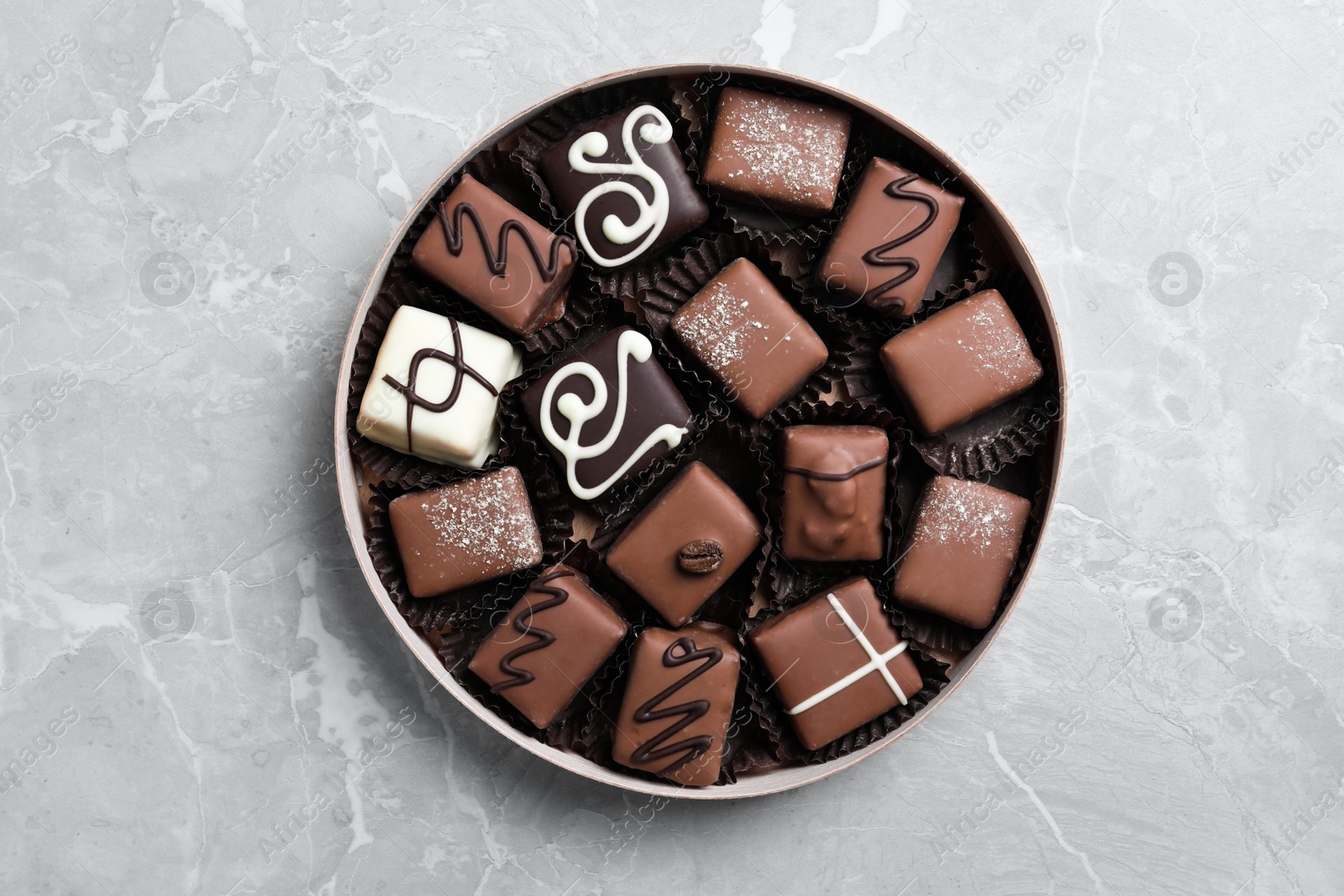 Photo of Box with tasty chocolate candies on light grey marble table, top view