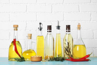 Photo of Different cooking oils on blue wooden table