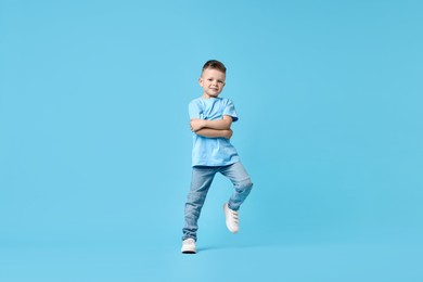 Happy little boy dancing on light blue background