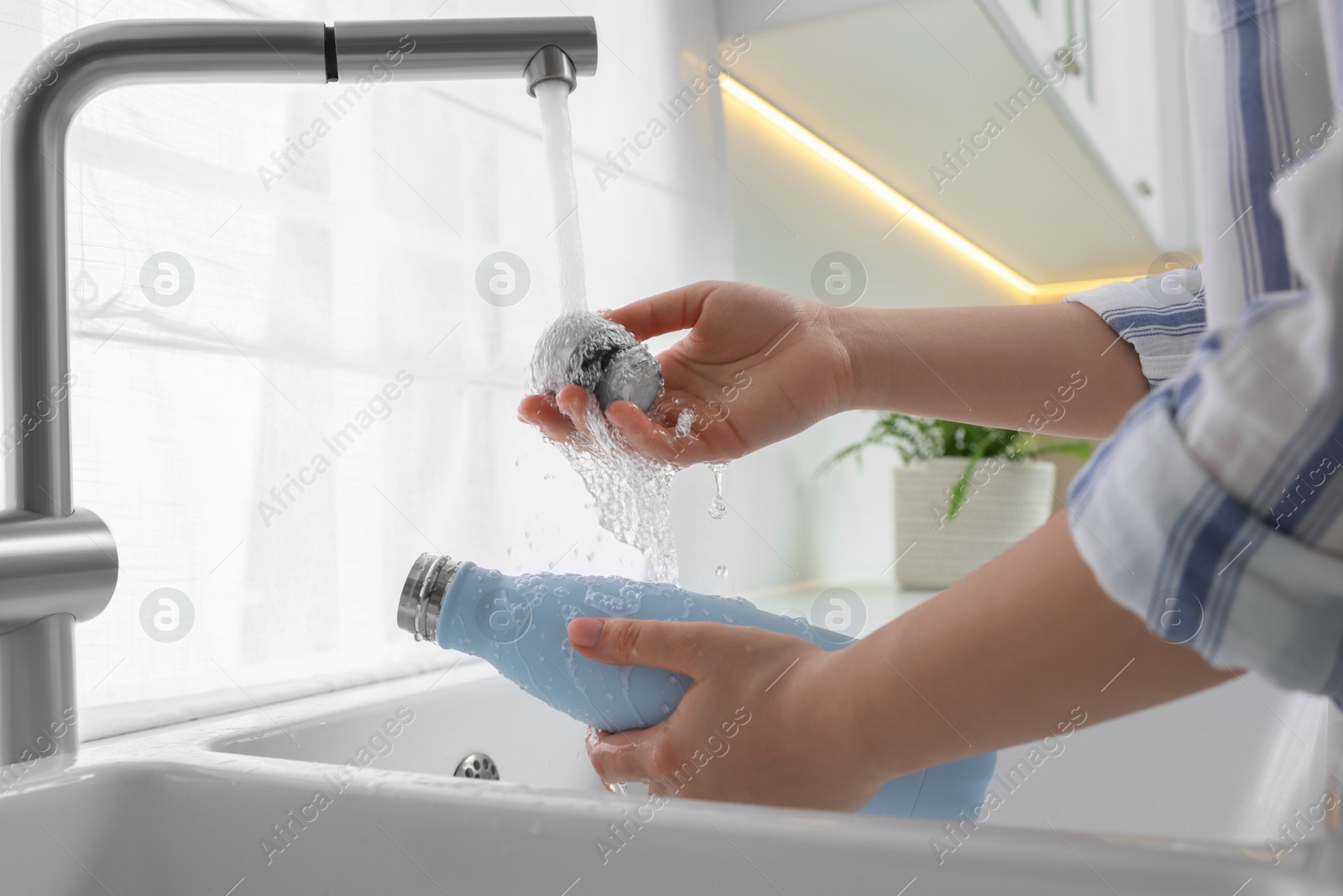 Photo of Woman washing thermo bottle in kitchen, closeup