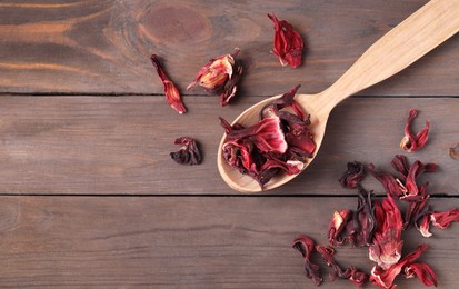 Spoon with dry hibiscus tea on wooden table, flat lay. Space for text