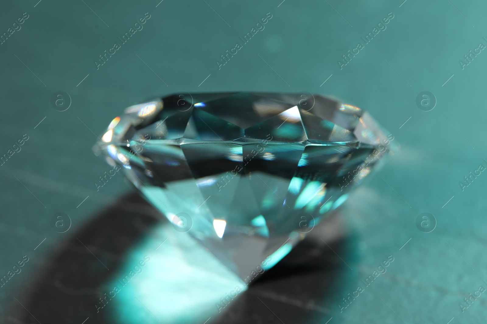 Photo of Beautiful dazzling diamond on green textured background, closeup