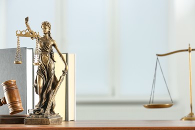 Photo of Figure of Lady Justice, gavel and books on table indoors, space for text. Symbol of fair treatment under law