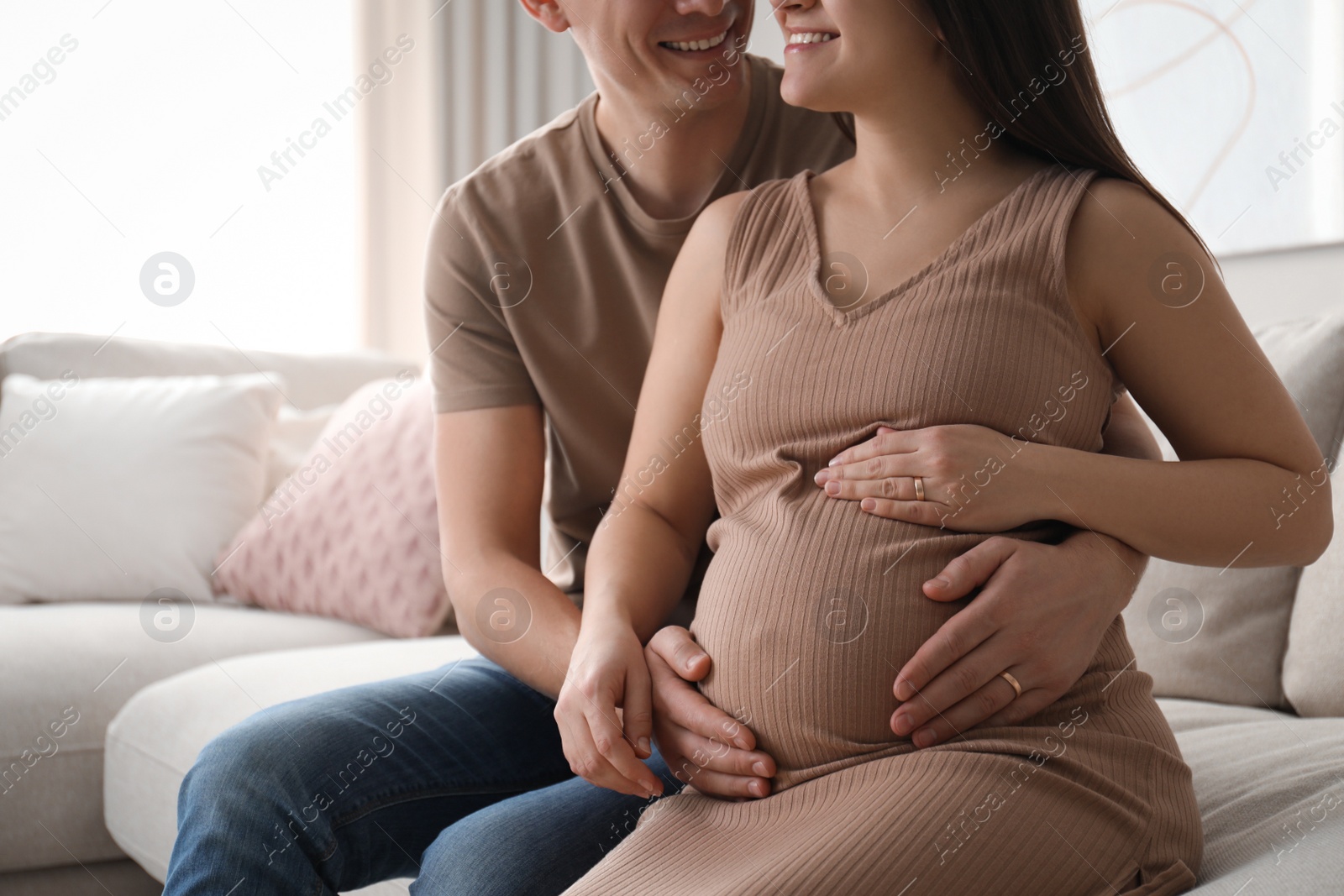 Photo of Man touching his pregnant wife's belly at home, closeup