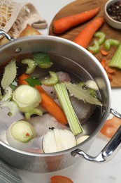 Photo of Pot and different ingredients for cooking tasty bouillon on white table, above view