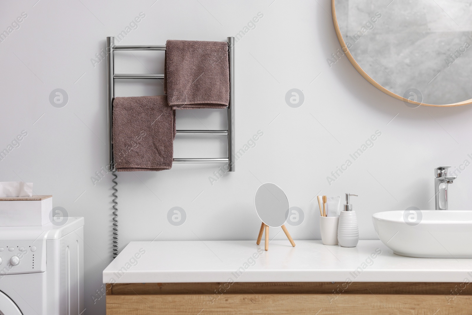 Photo of Heated towel rail with brown towels in bathroom