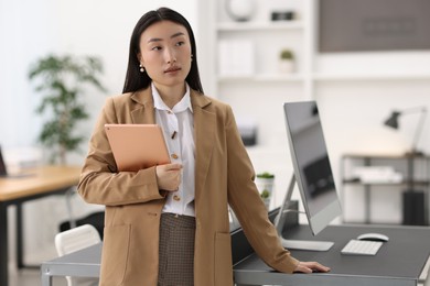 Portrait of beautiful businesswoman with tablet in office. Space for text