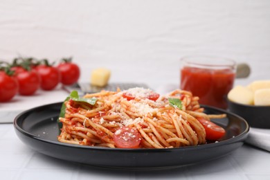 Tasty pasta with tomato sauce, cheese and basil on white tiled table, closeup