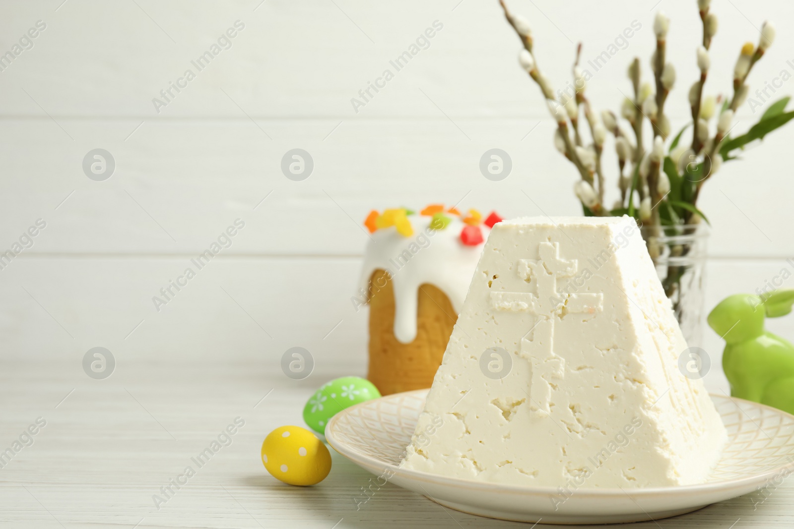Photo of Traditional cottage cheese Easter paskha and eggs on white wooden table, space for text