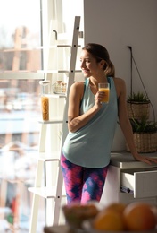 Young woman in fitness clothes with glass of juice at home