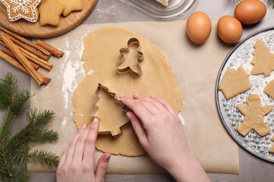 Photo of Woman making Christmas cookies with cutters at grey table, top view