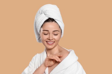 Photo of Portrait of attractive young woman in bathrobe with towel on beige background. Spa treatment
