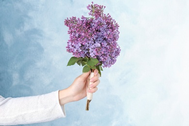 Photo of Young woman holding beautiful blossoming lilac on color background. Spring flowers