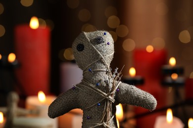 Photo of Voodoo doll with pins and dried flowers in dark room, closeup. Curse ceremony