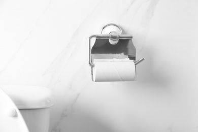 Photo of Holder with empty toilet paper roll on wall in bathroom