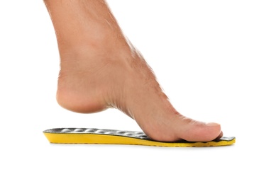 Man fitting orthopedic insole on white background, closeup. Foot care