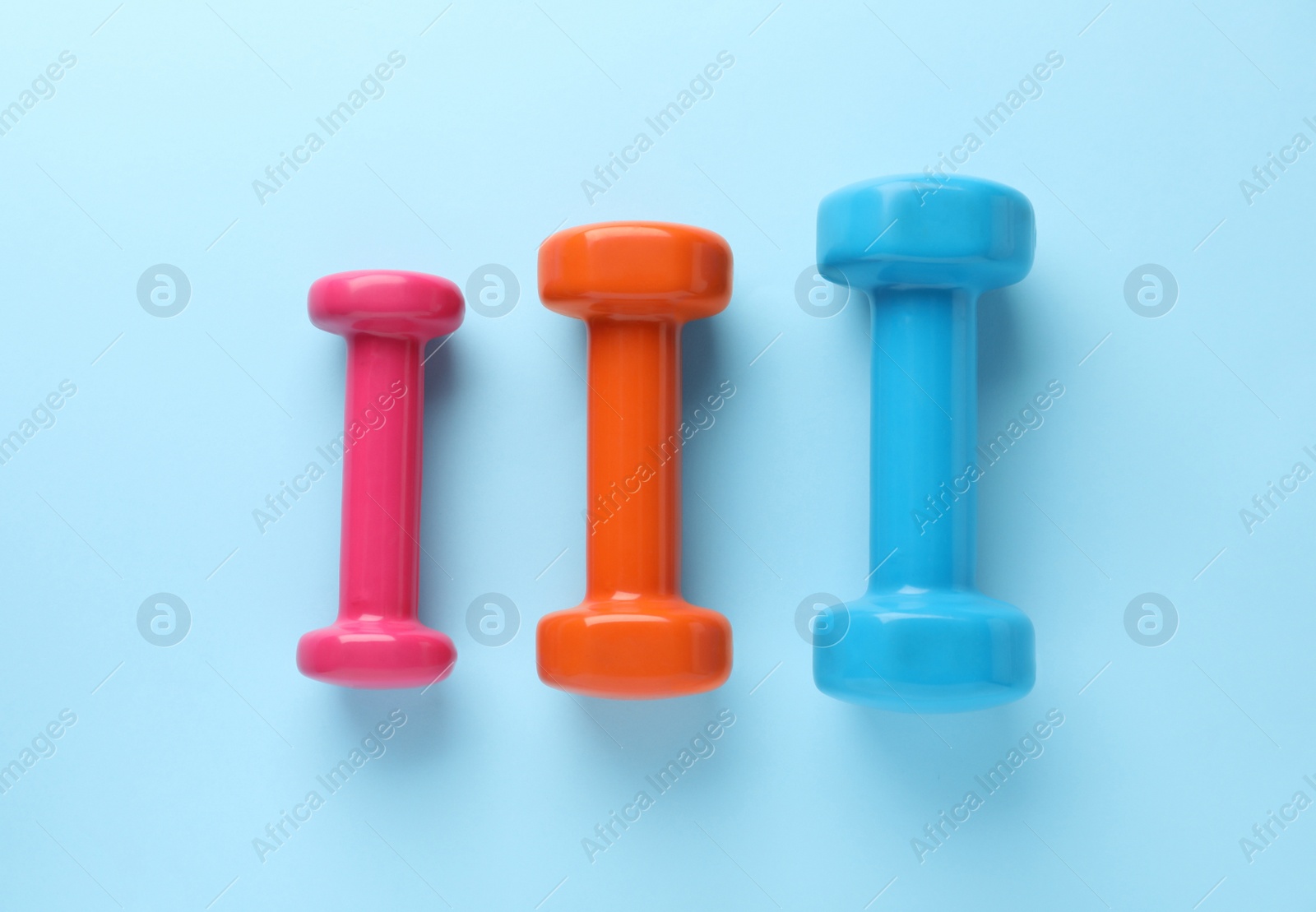 Photo of Different stylish dumbbells on light blue background, flat lay