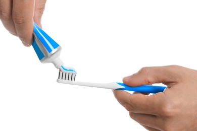 Man applying toothpaste on brush against white background, closeup