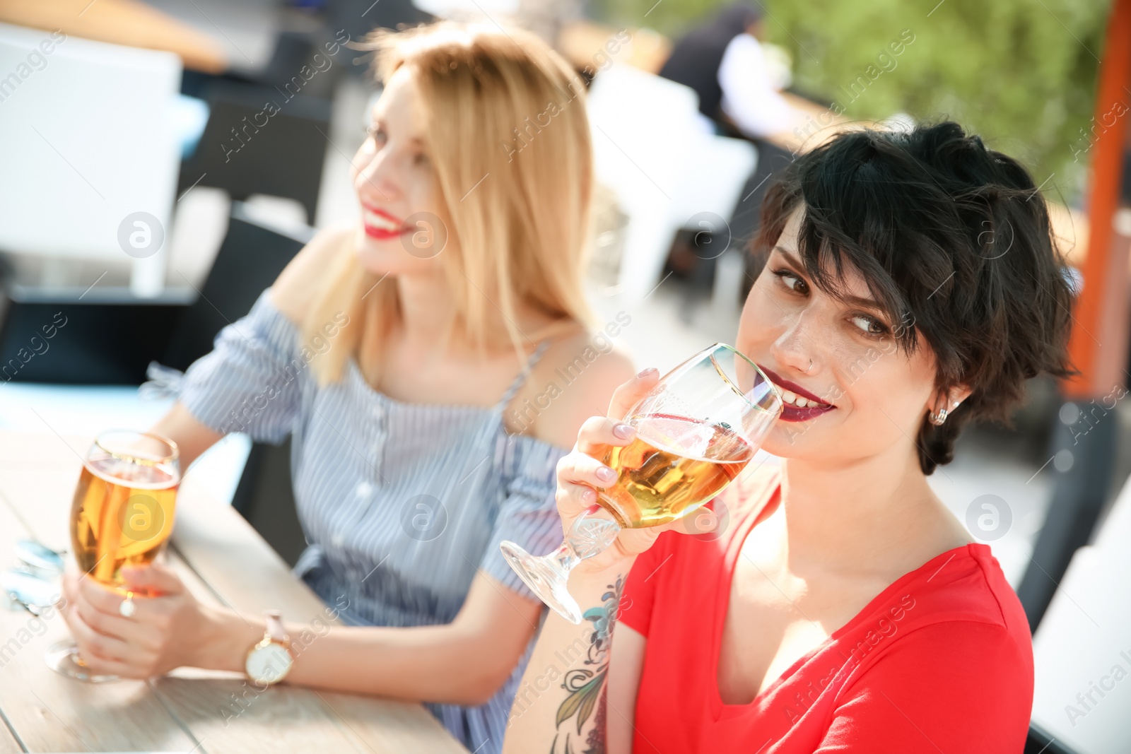 Photo of Young women with glasses of cold beer at table