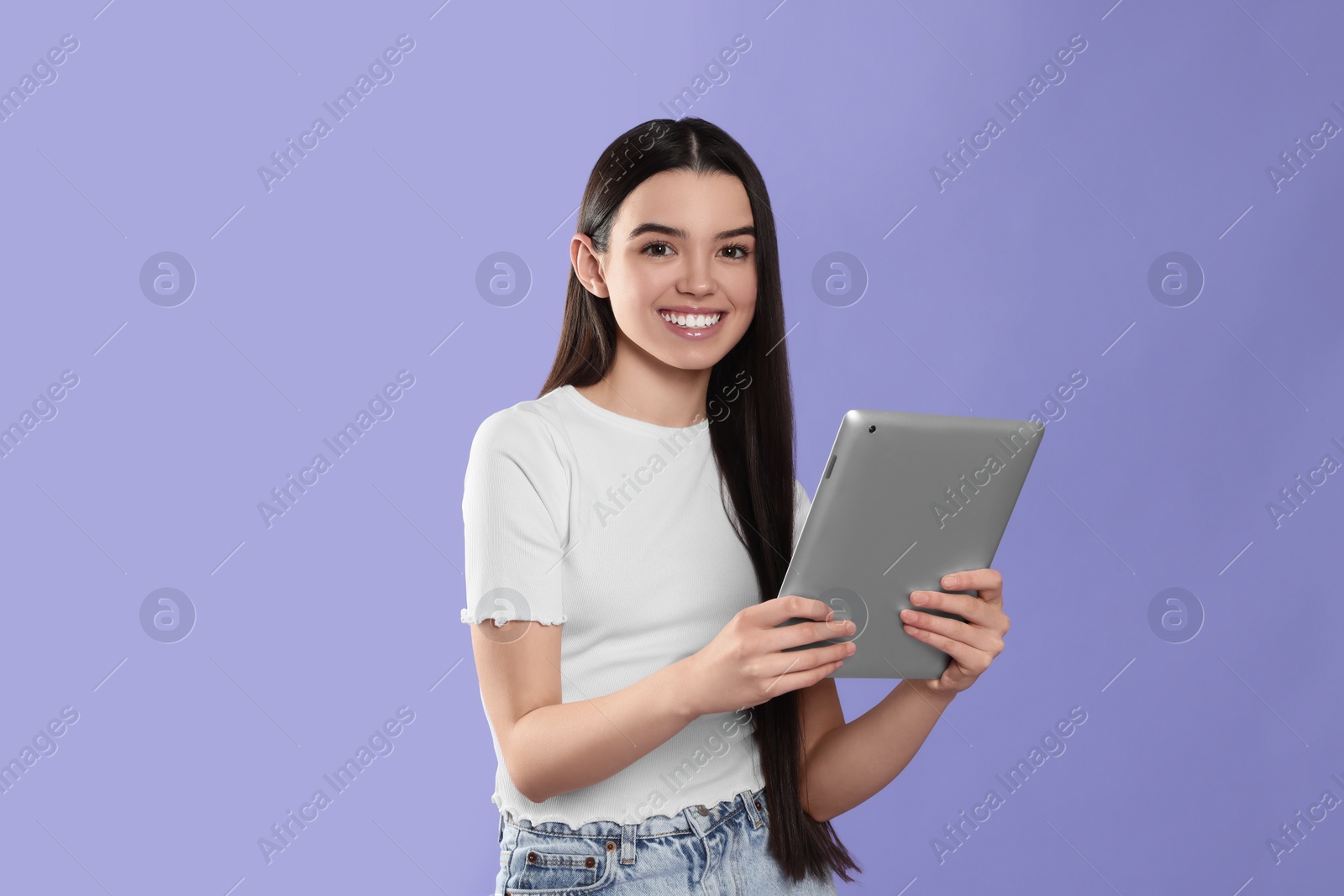 Photo of Teenage girl using tablet on violet background. Space for text
